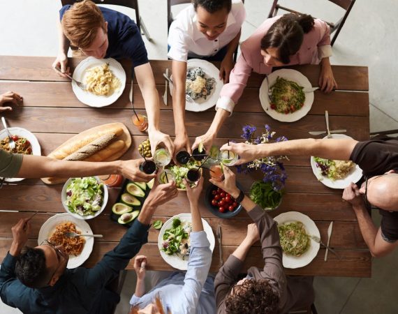 A vibrant group cheers over a delicious meal, showcasing friendship and togetherness.