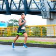 Athlete running on a city street during a marathon under a bridge.